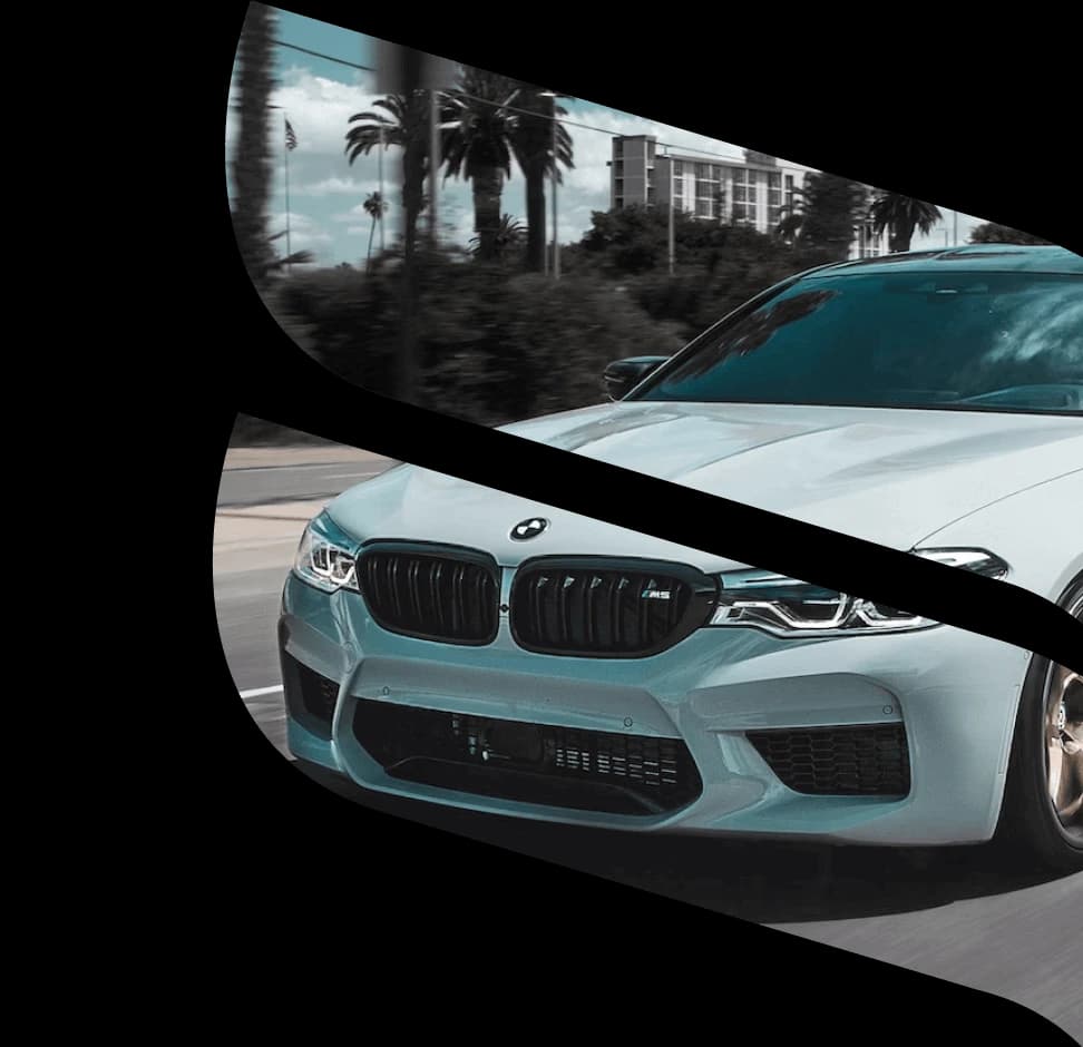 A white BMW car is shown on a road with palm trees and buildings in the background